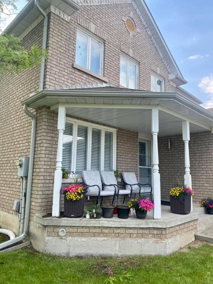 White eavestrough and downspout on a brick two-storey home with a covered porch.