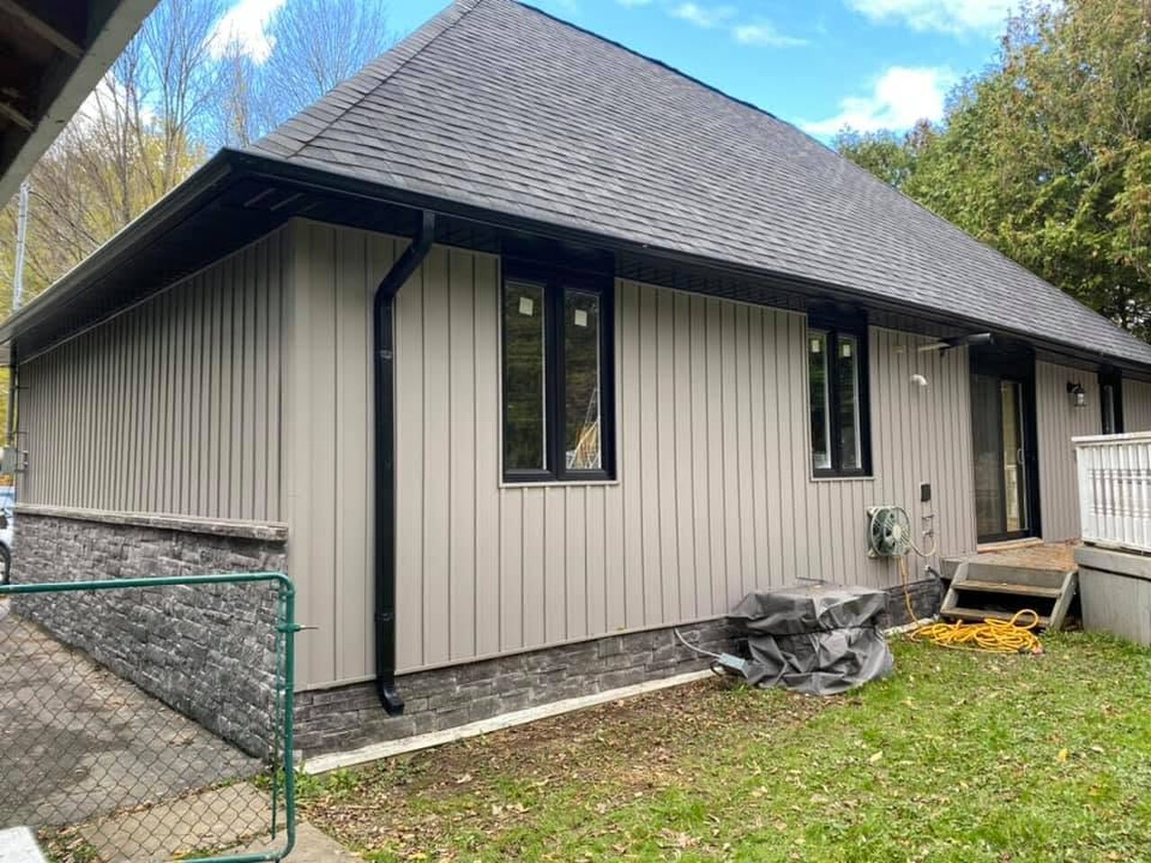 Side elevation with finished taupe board-and-batten siding and dark trim.