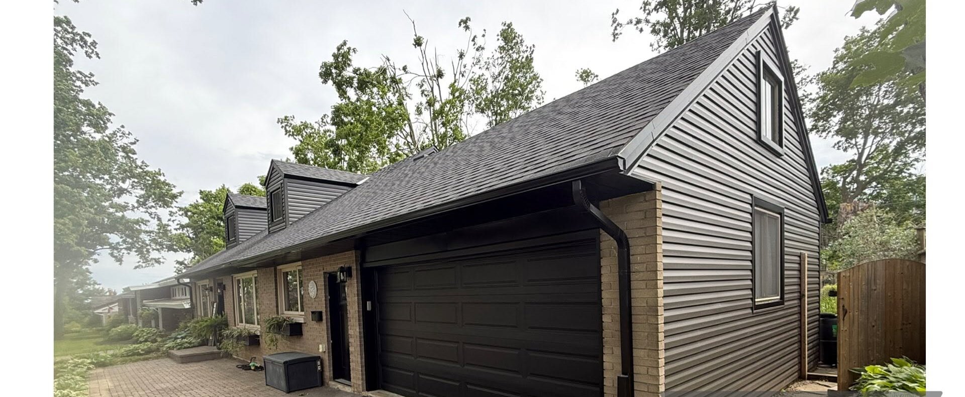 Completed garage with dark vertical siding, dark trim, and a black overhead door.