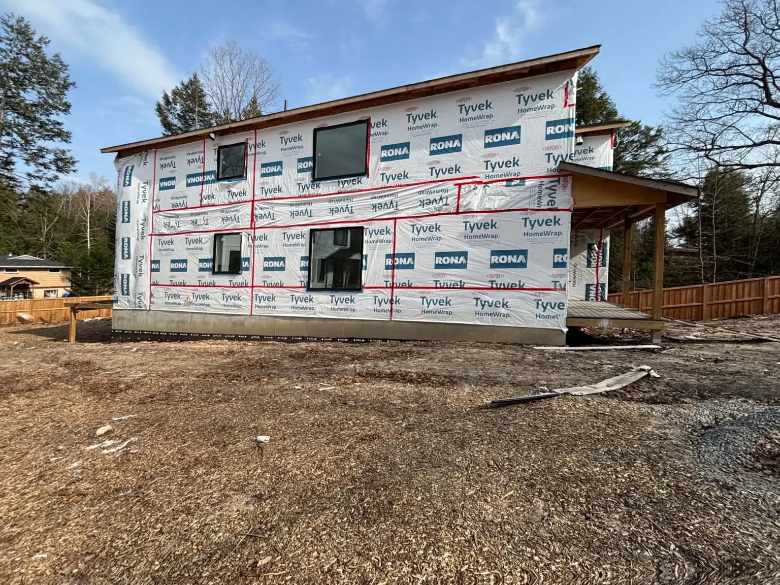 Two-storey home wrapped and prepared for siding installation.