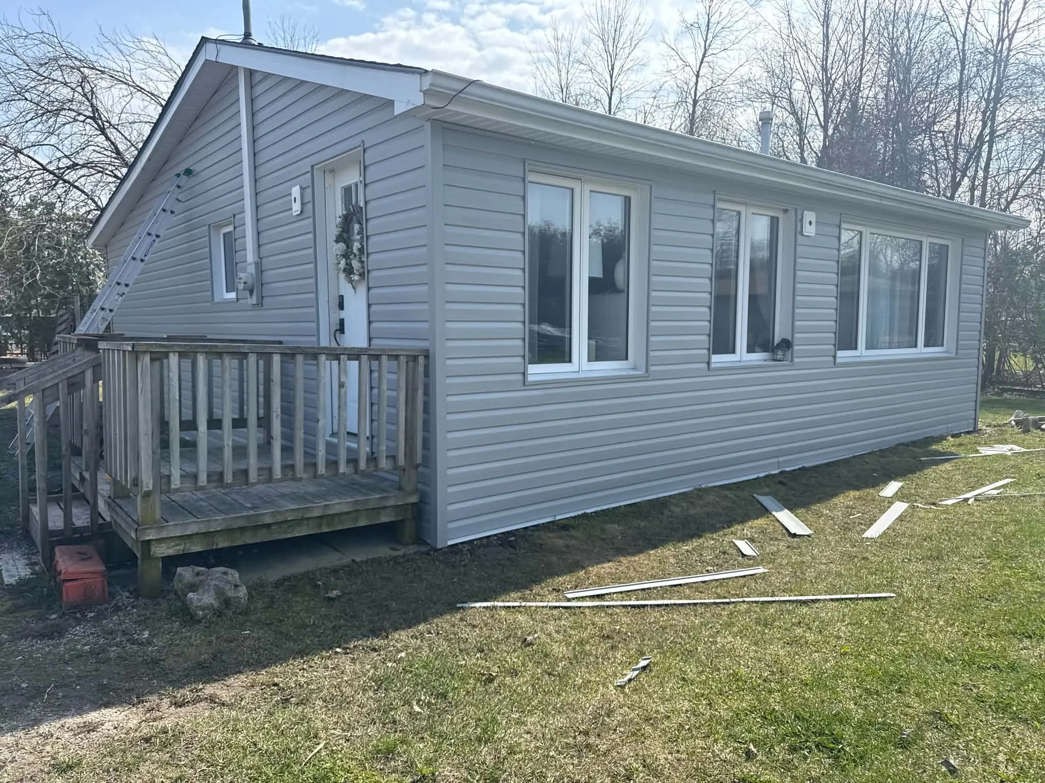 Finished grey siding, soffit, fascia, and white eavestrough work on a home exterior.