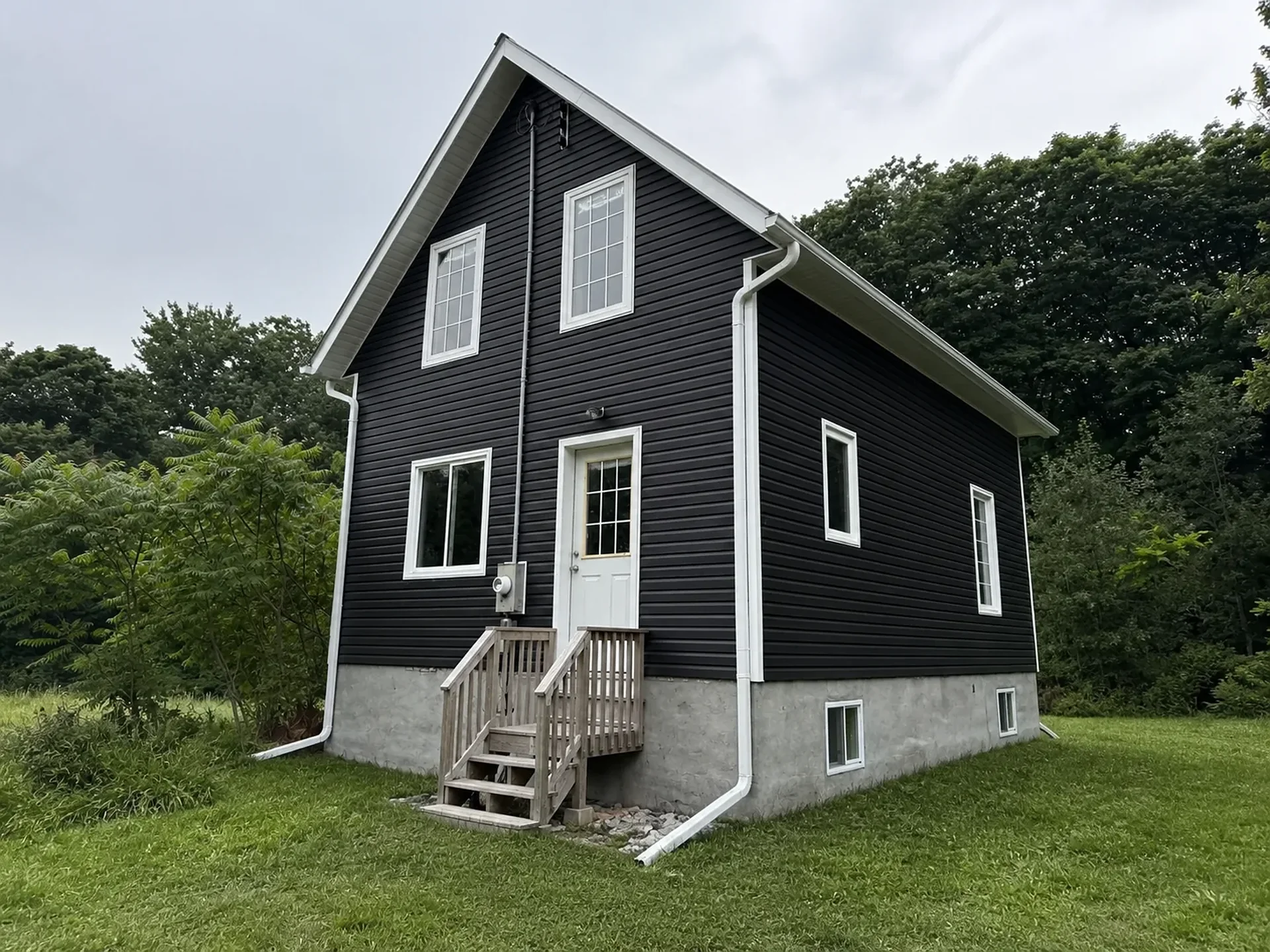 Finished dark siding, white trim, eavestrough, and downspouts on a Grozelle Exterior project.