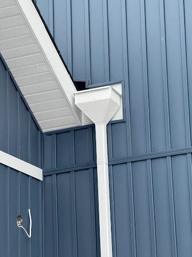 Black downspout detail against blue board-and-batten siding.