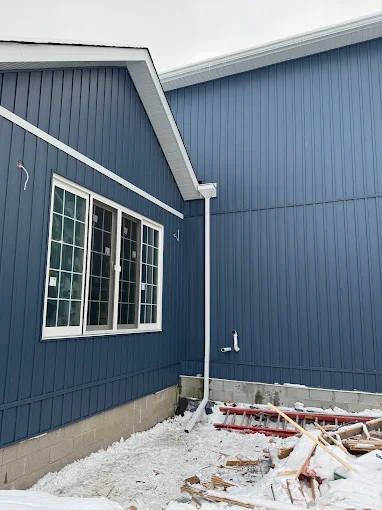 Close view of blue board-and-batten siding installation beside dark trim.