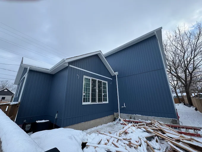 Front and side view during blue board-and-batten siding installation.