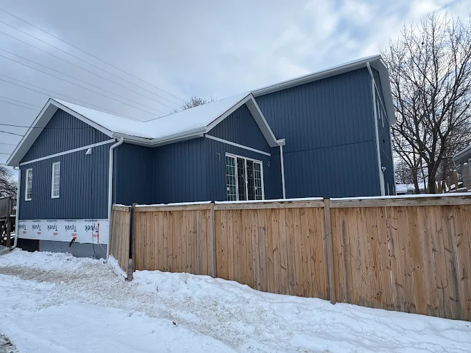 Rear elevation during blue board-and-batten siding installation.