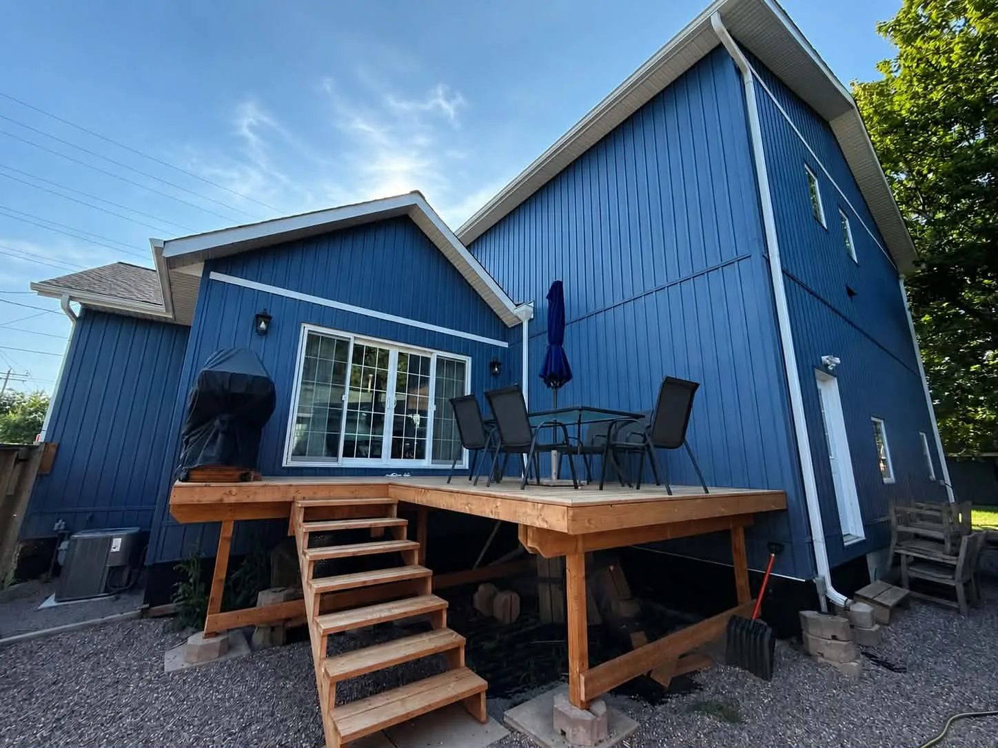 Wide rear deck view with completed blue board-and-batten siding and dark trim.