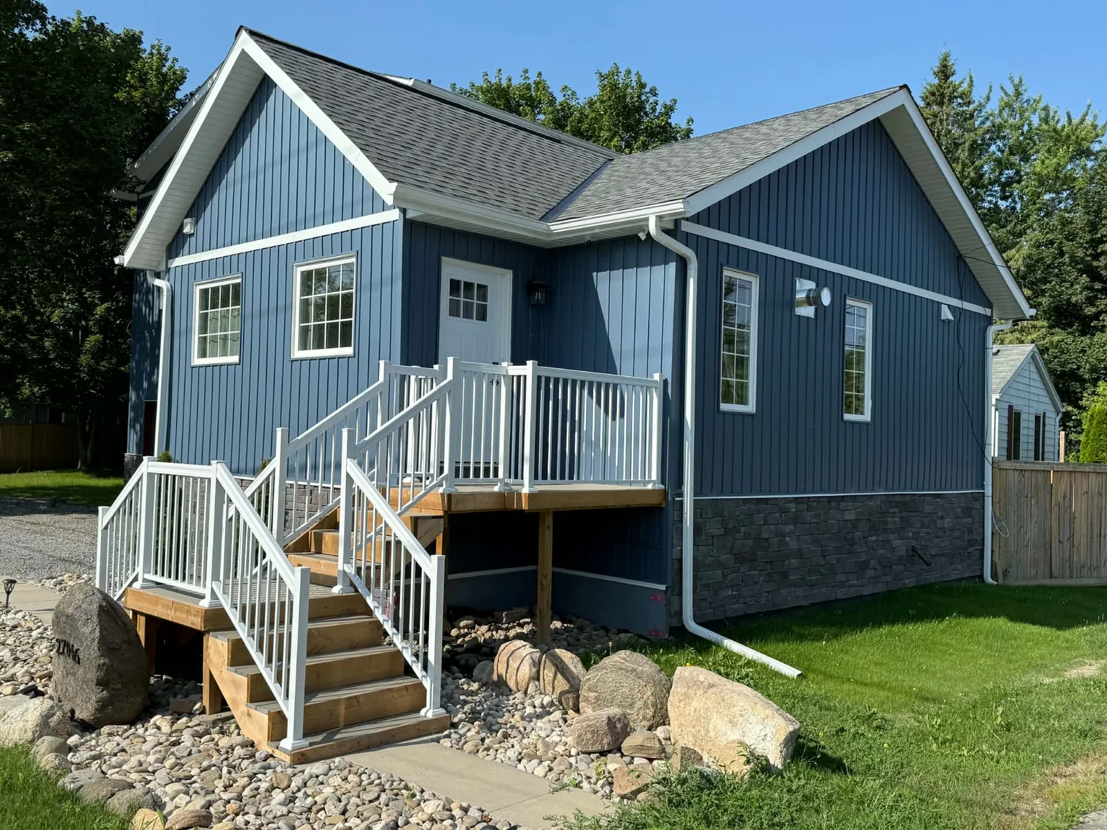 Finished blue board-and-batten siding and dark trim around the front entry.