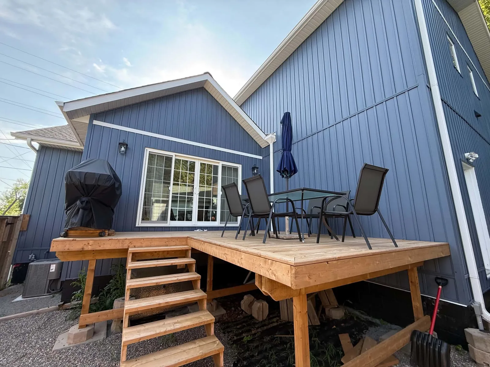 Rear deck framed by finished blue board-and-batten siding and dark trim.