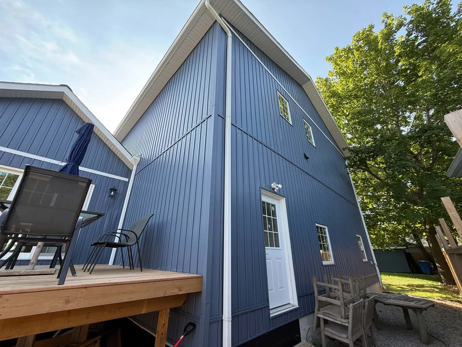 Finished blue board-and-batten siding across the rear wall of the home.