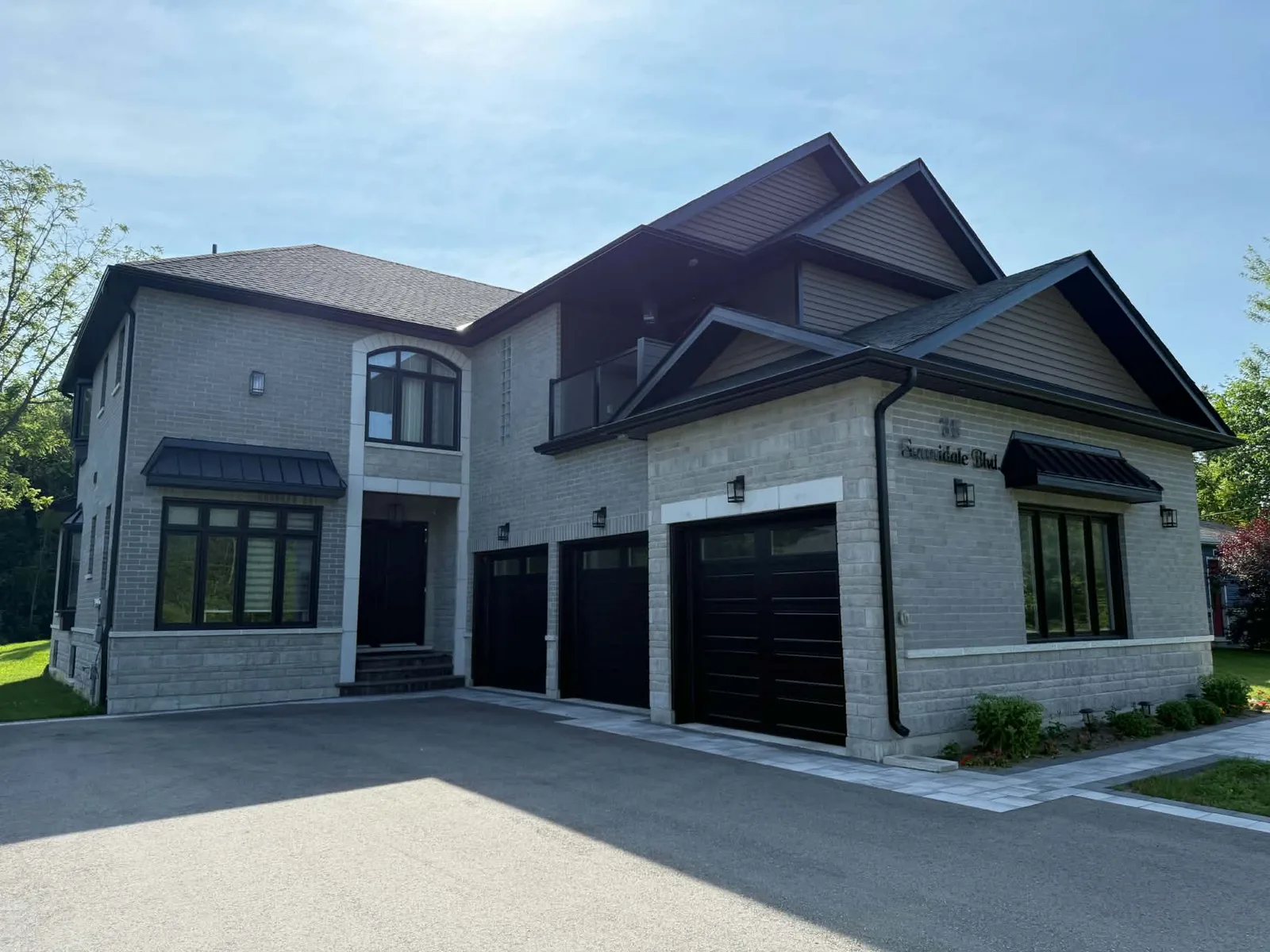 Front driveway view of a brick home with completed dark roofline and window accents.