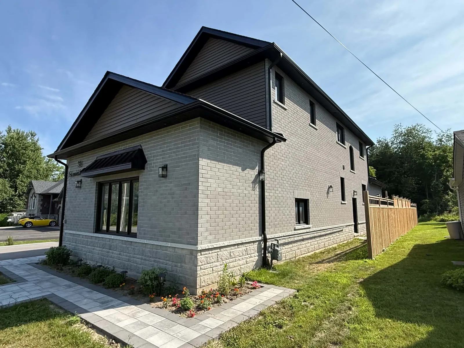 Brick two-storey home with finished dark roofline and window trim details.