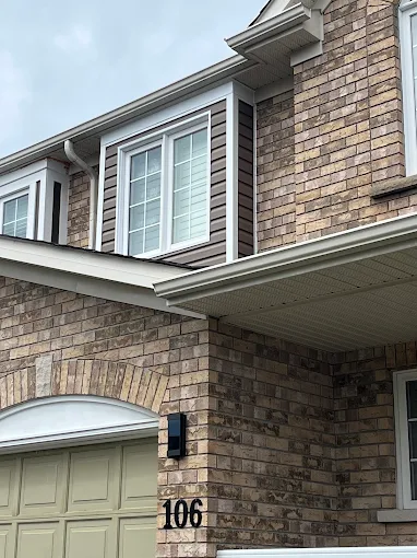 Eavestrough and downspout detail on the brick two-storey home.