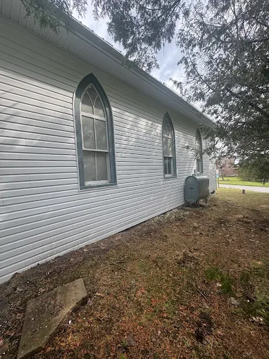 Side exterior of the church building with finished siding and roofline.