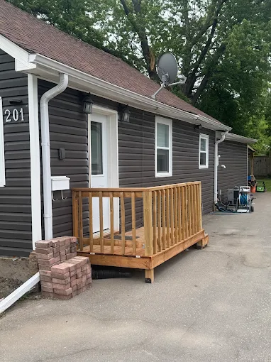 Small bungalow with finished dark siding, white trim, and white roofline drainage.