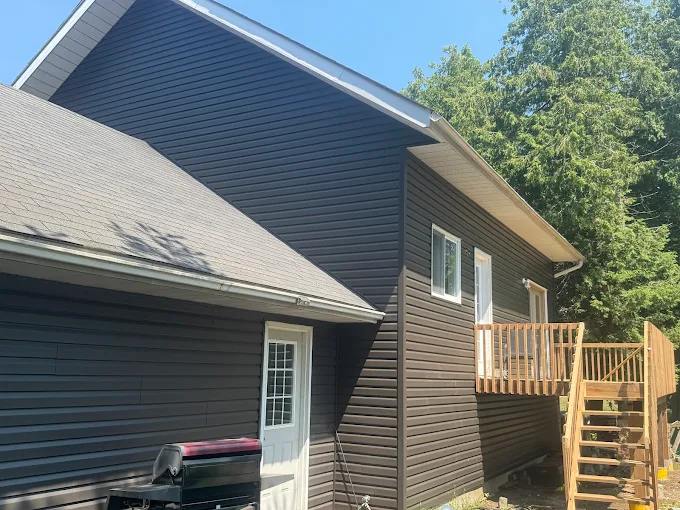 Dark siding and roofline detail above an attached brick garage.