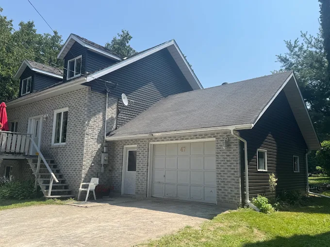 Brick home and attached garage with finished dark siding and trim.