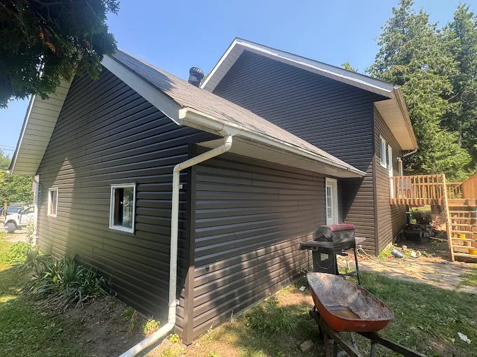 Side and garage elevations of a brick home with dark siding and trim.