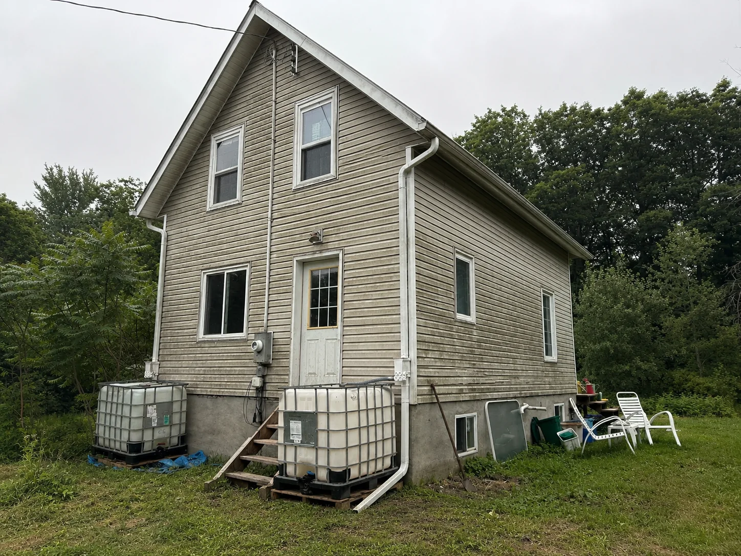 Weathered light siding on the main elevation before the exterior transformation.
