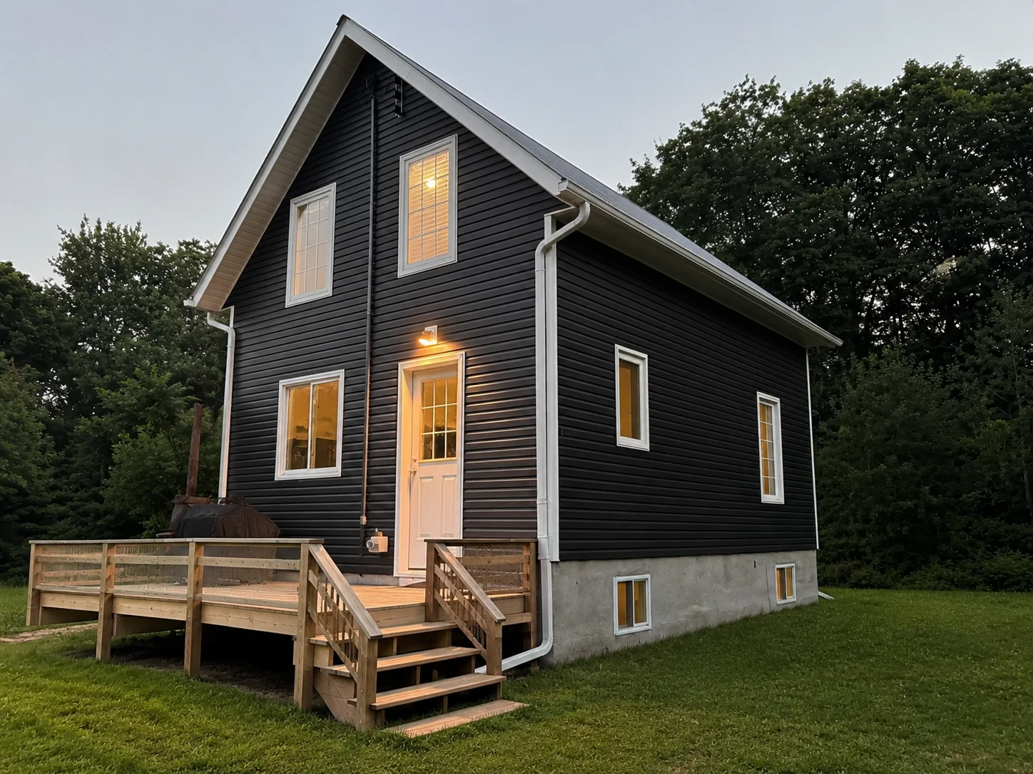 Finished dark siding in an evening view with warm lights visible through the windows.