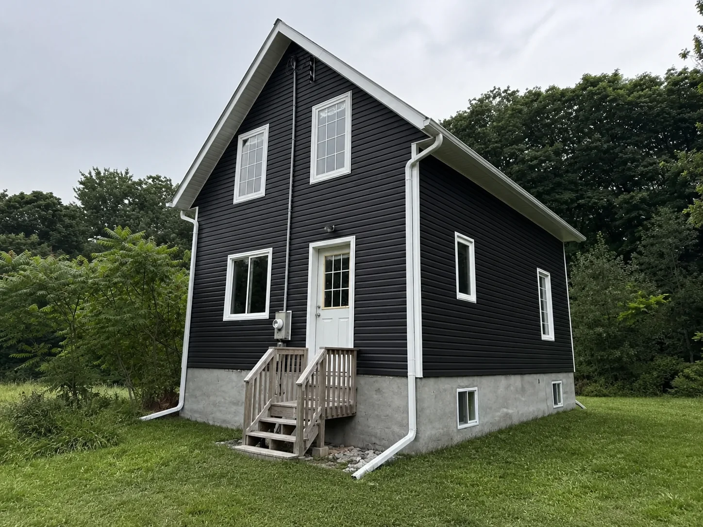 Finished main elevation with dark horizontal siding and contrasting white trim.