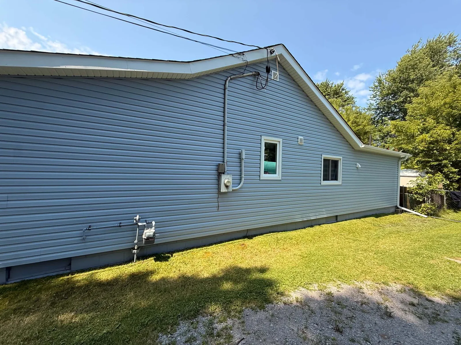 Wide view of the bungalow long wall after the light-grey siding was completed.
