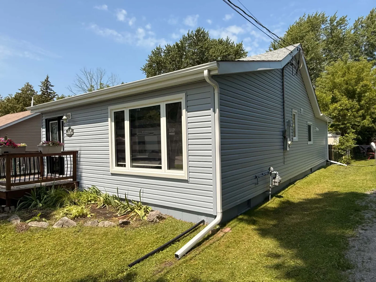 Finished light-grey siding around the rear deck and windows of a bungalow.
