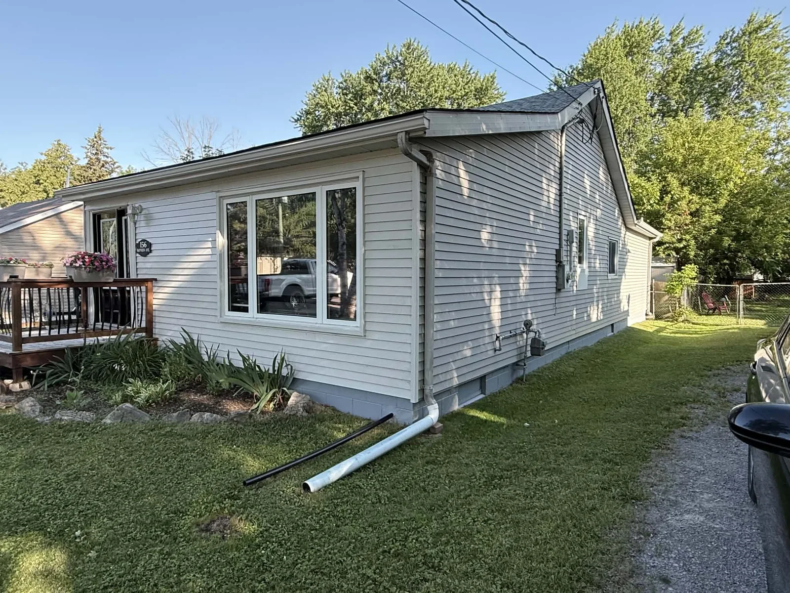 Long side elevation finished with light-grey horizontal siding and white window trim.