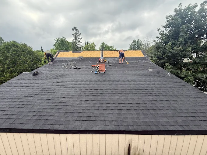 Asphalt shingles being installed across a sloped roof.