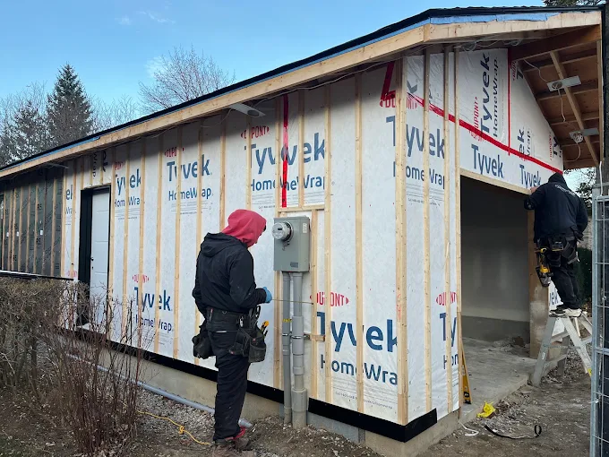 Exterior wall being prepared with insulation and wrap during siding work.