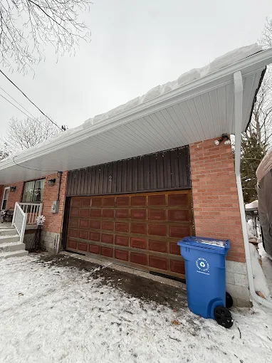 White eavestrough along the roof edge of a brick garage in winter.