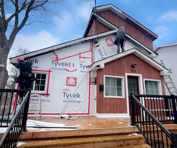 Exterior crew working on siding wrap at a red home.