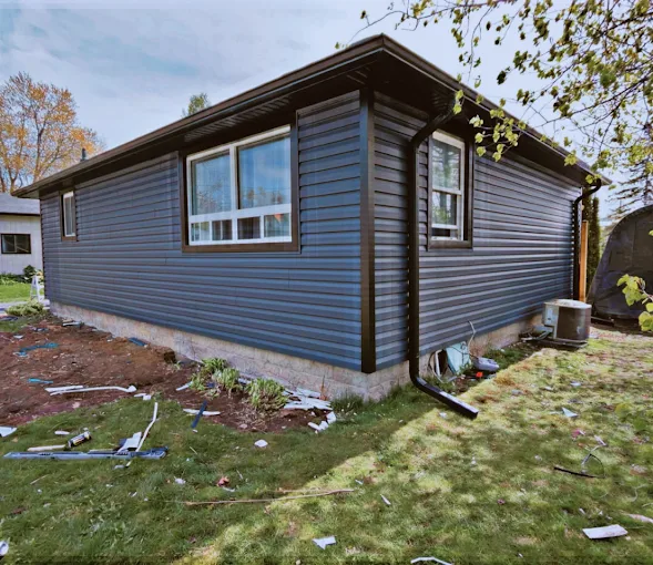 Bungalow finished with dark blue horizontal siding and light trim.
