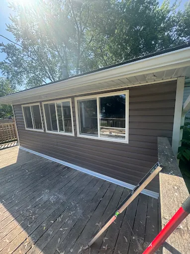 Dark horizontal siding finished on a wall below a raised deck.