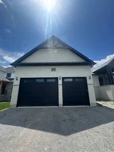 Detached garage with dark overhead doors and a finished light roofline.
