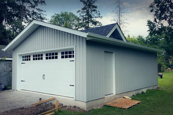 Detached garage finished with vertical siding and a dark overhead door.