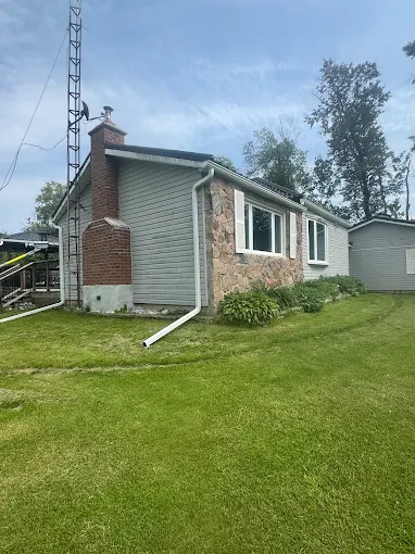 Brick bungalow with grey horizontal siding and white roofline trim.