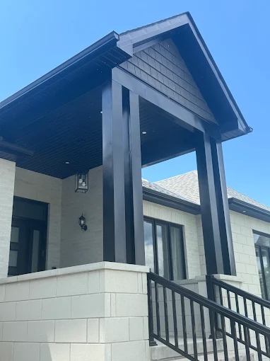 Covered porch showing finished soffit, fascia, roof edge, and posts.
