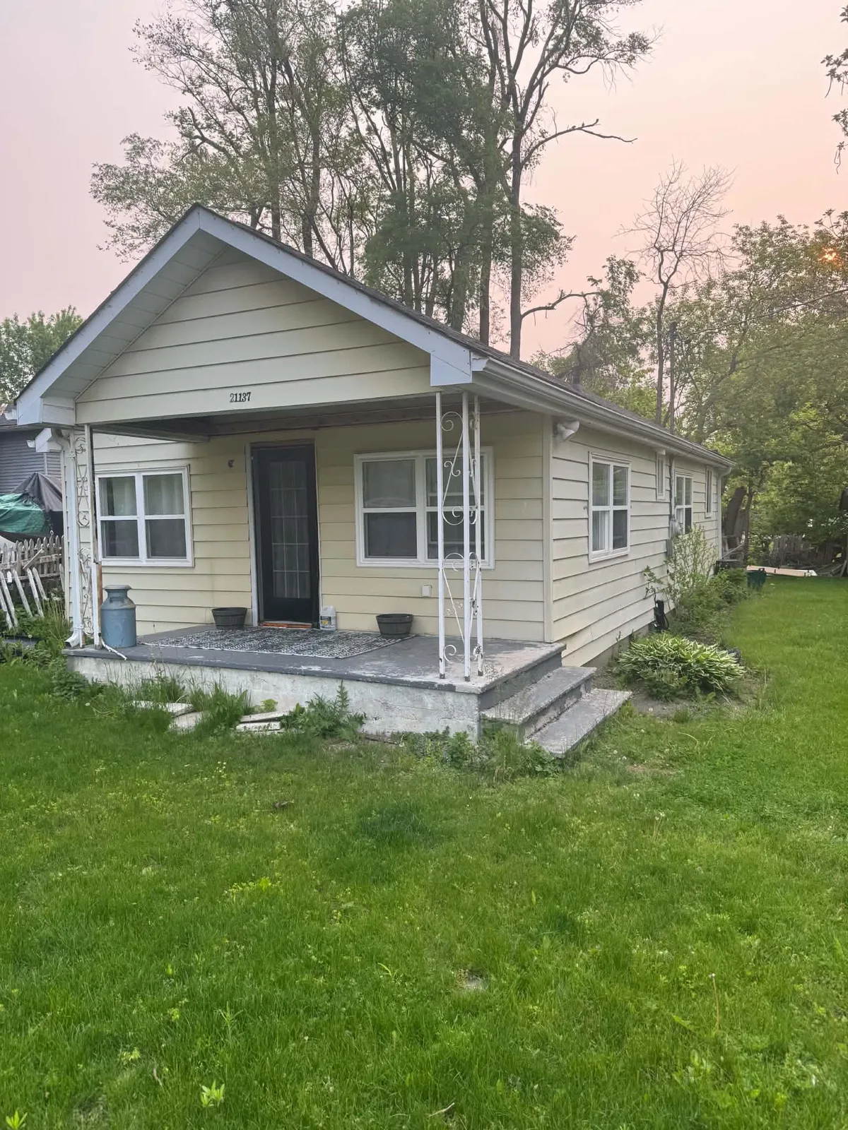 Wide front view of the tan-sided cottage before the transformation.
