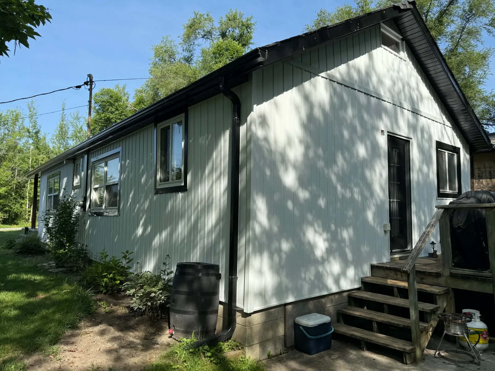 Rear and side elevations finished with white siding and black trim.