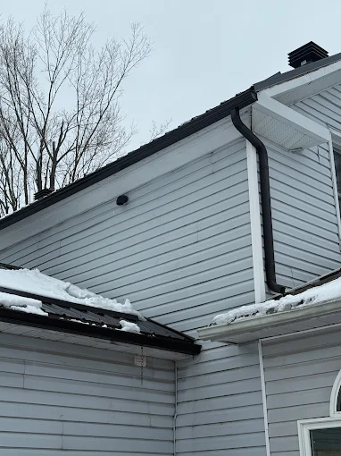 Black downspout detail against finished white siding.