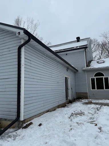 White-sided home with a contrasting black eavestrough and downspout.