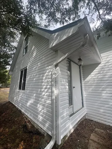 Side angle of the same house with white horizontal siding and trim.