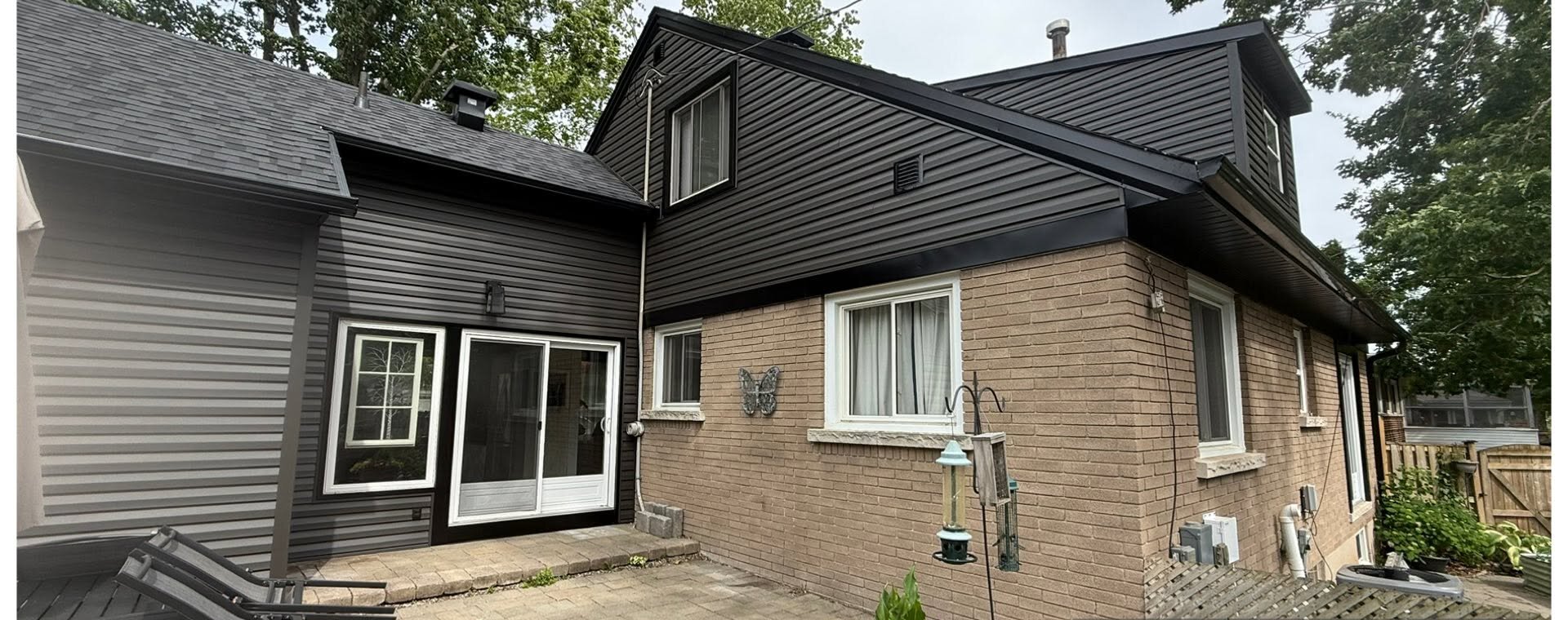 Finished dark horizontal siding joined to an existing brick home.