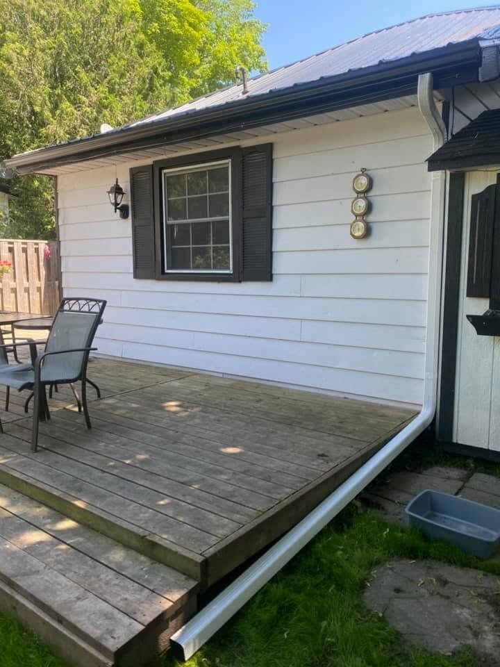 White siding and dark roof-edge trim on a home beside a wood deck.